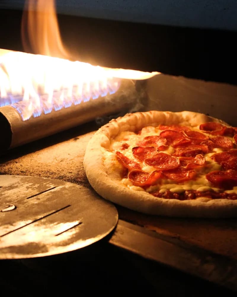 Pizza saliendo del horno a leña